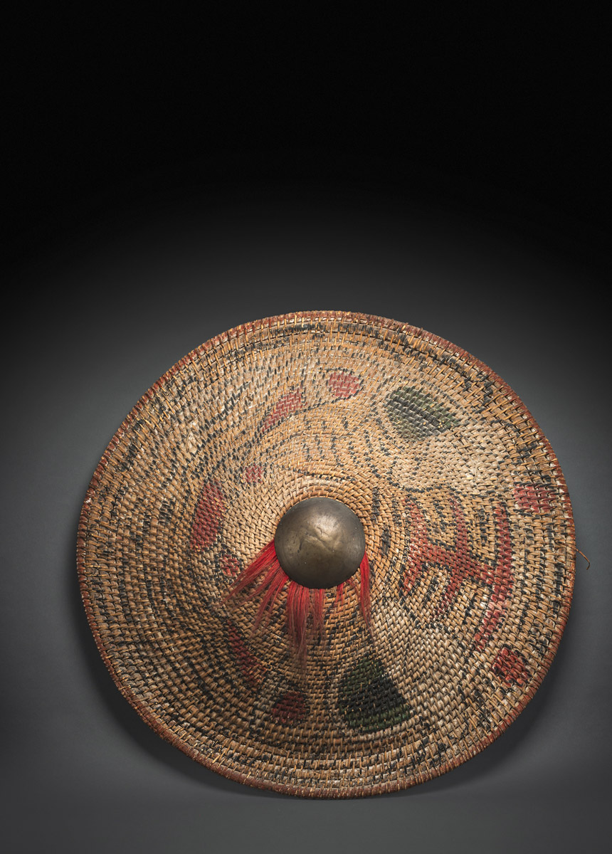 A RARE ARMY SHIELD MADE OF WOVEN RATTAN WITH POLYCHROME PAINTED TIGER HEAD AND METAL FITTING