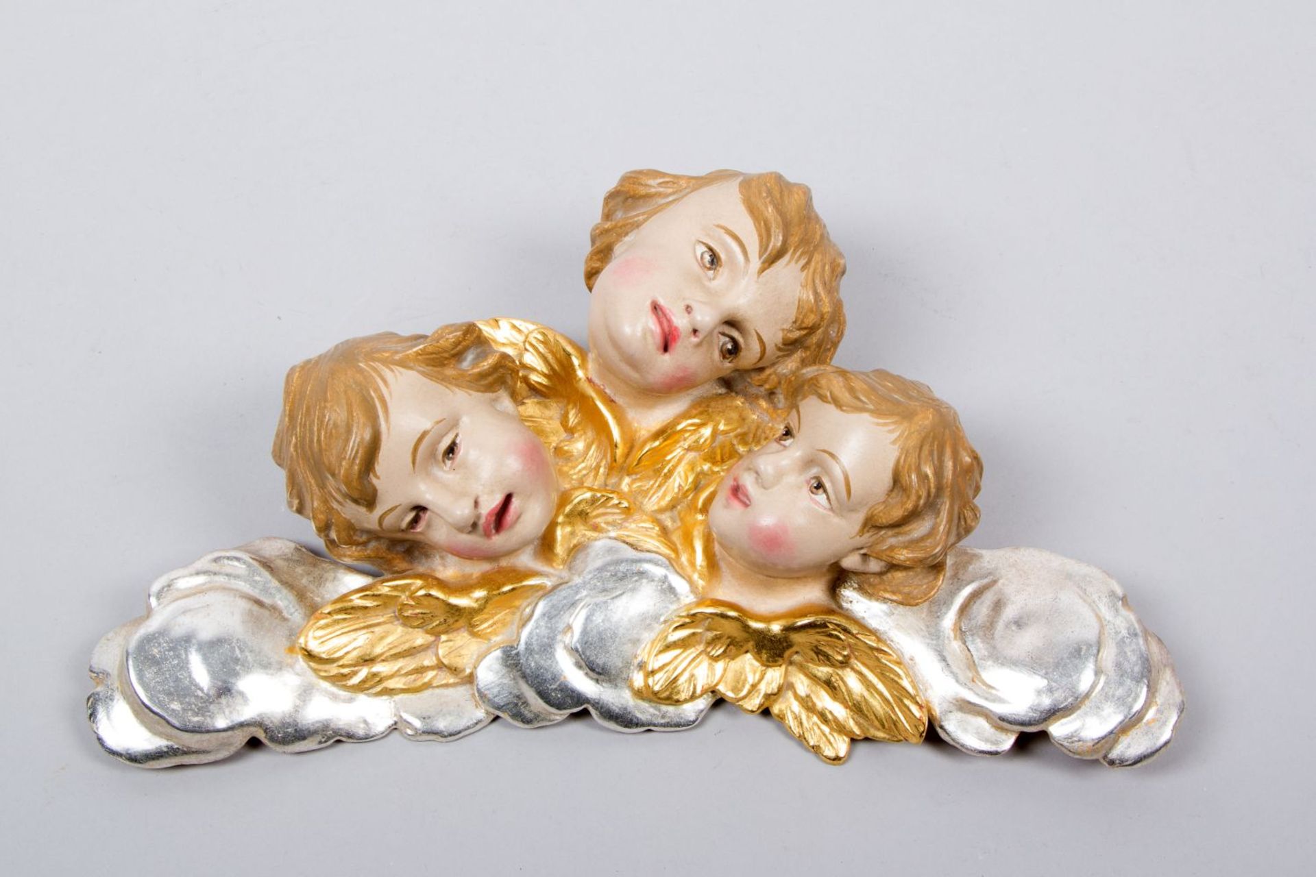 Drei Engelsköpfe auf Wolkensaum Holz, geschnitzt. Farb-, Silber- und Goldfassung. 20. Jh. B. 30 cm.