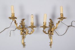 Ein Paar Wandappliquen Messing, vergoldet. 2-flammig. Geschweiftes Gestell. Blatt- und Blütendekor. 
