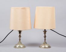 Ein Paar Tischlampen Metall, versilbert. 1-flammig. Kerzenleuchter als Füße. Mit Schirmen. H. 36 cm.