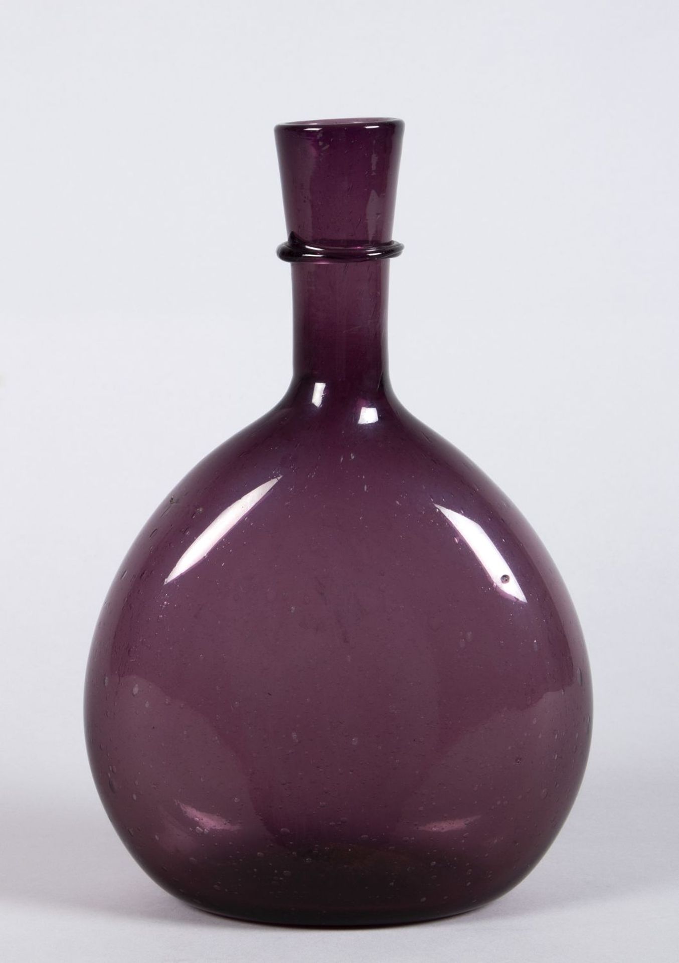 Plattflasche Violettfarbiges Glas. Tropfenförmige, zweiseitig stark abgeflachte Wandung mit Röhrenha