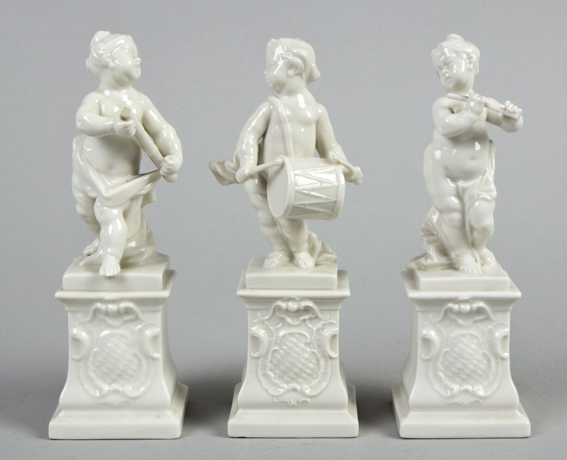 Putto mit Trommel, Putto mit Flöte und Putto mit Fagott Drei Figuren auf Sockeln. Geprägtes Rautensc