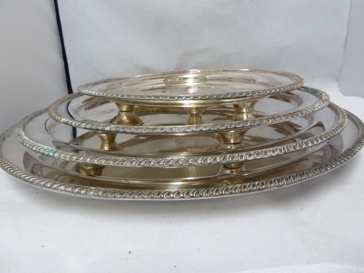 A graduated set of four silver plated salvers, circular with gadrooned edge, the centre engraved