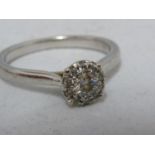A diamond illusion 'solitaire' ring, ten small diamonds set around a central circular stone, white