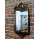 A Chinoiserie black japanned framed looking glass, decorated with gilded raised figures in a