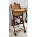 Victorian oak dolls high chair with cast roller feet.