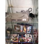 Sony PlayStation one with controller and shelf of PlayStation 2 games.