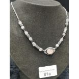 Ornate white metal possible silver necklace set in pink stone effect .