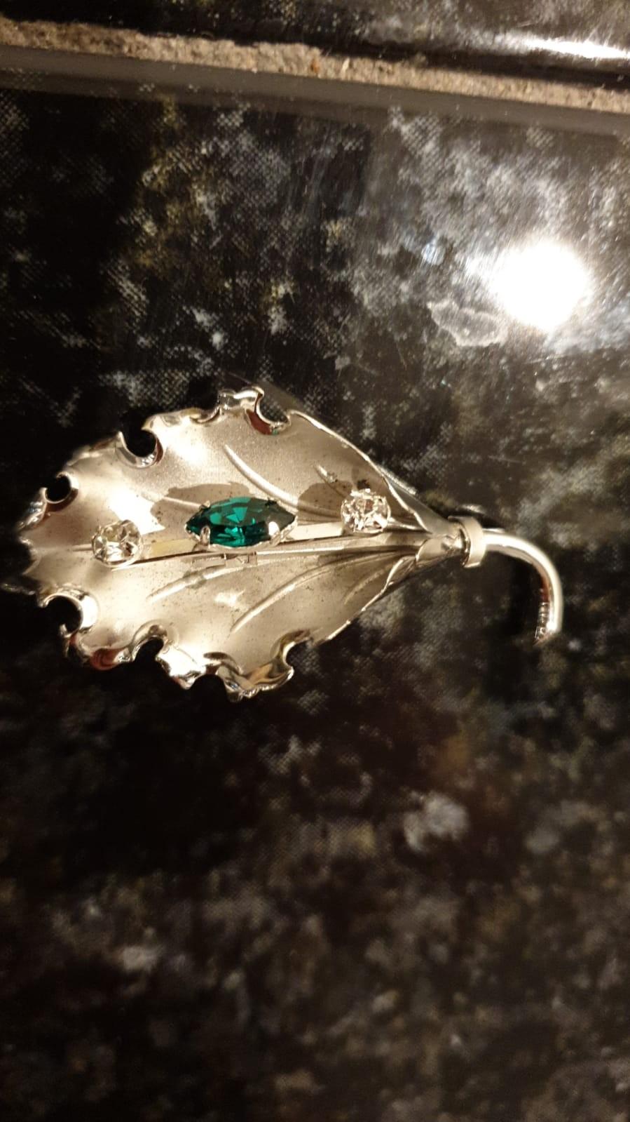 Silver leaf brooch set in green stone and 2 clear stones.