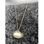 9ct gold chain on a large yellow metal pendant set in mother of pearl.