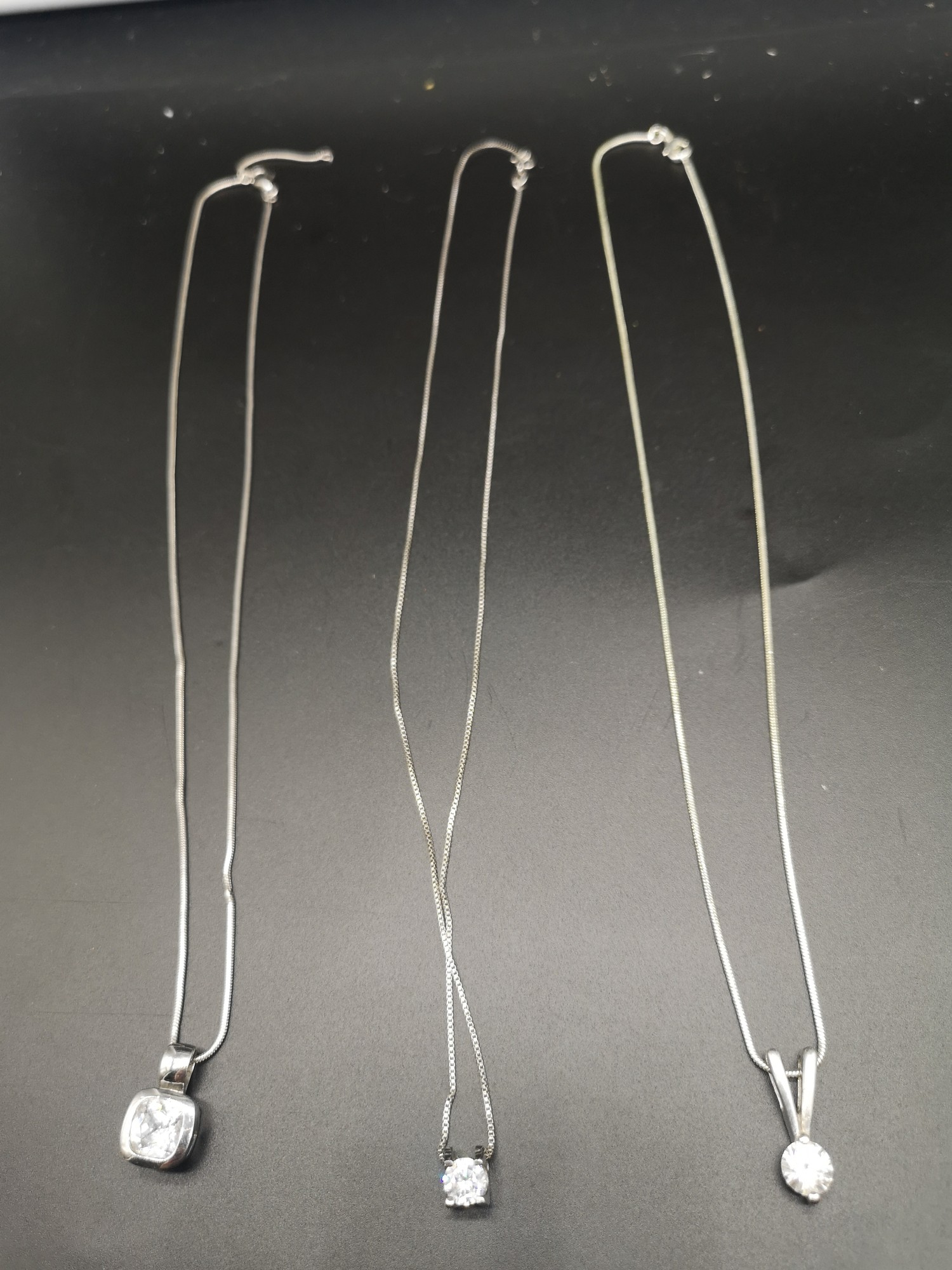 3 silver necklaces with pendants.