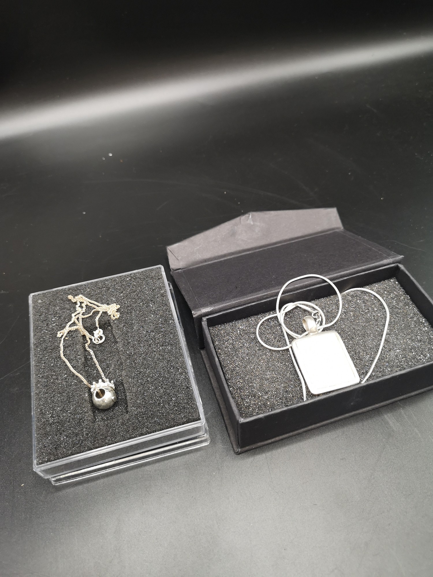 2 silver chains one set with mother of pearl pendant and other bling pendant.