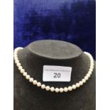 Pearl necklace with yellow metal clasp .
