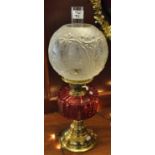 Early 20th Century brass double burner oil lamp with cranberry glass reservoir on brass conical