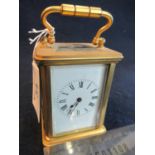 Miniature brass carriage clock with bevelled glass panels, Roman numerals and white face. (B.P.