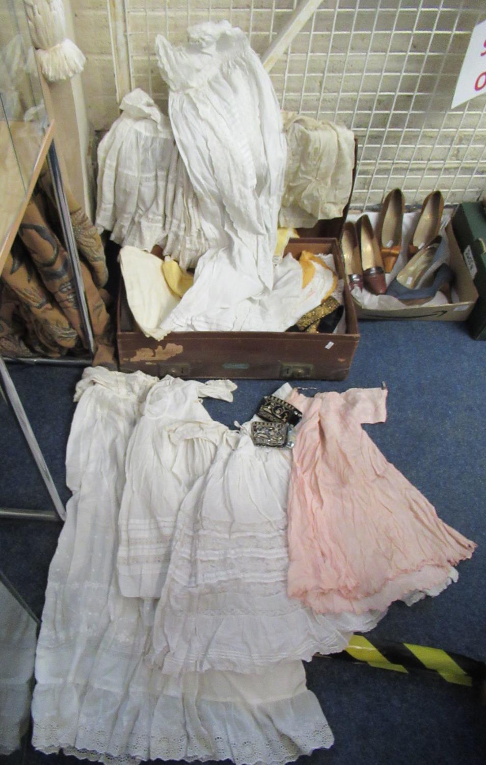 A vintage suitcase containing antique and vintage children's clothing, tableware and a wire