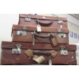 Three vintage tan leather suitcases, each with carrying handles and metal locks and clasps.
