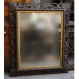 Late 19th/early 20th Century wall mirror of rectangular form the wooden frame carved and pierced