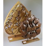 Two similar modern carved leaf sculptures, one encased in an upside down heart. On rectangular