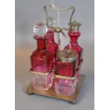 Silver plated and cranberry glass four piece cruet set on square stand with bun feet. (B.P. 21% +