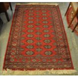 Middle Eastern design red ground carpet with central field of stylised guls and geometric