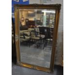 Large modern gilt framed bevel plate mirror with relief moulded scroll and foliate decoration. (B.P.