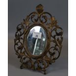 Gilt metal easel table mirror, having pierced scroll and foliate decoration, of oval form. (B.P. 21%