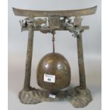 Chinese yellow metal temple bell on gateway arch stand with applied metal dragon motifs. 33cm high