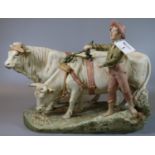 Royal Dux porcelain figure group of a young boy with a pair of oxen, on an oval naturalistic base.