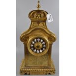 Brass mantel clock with scrolled pediment above Roman ceramic face and pierced panels below, brass