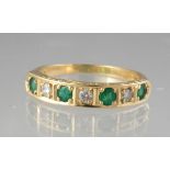 Emerald and diamond half eternity style ring of four emeralds and three diamonds set in yellow metal