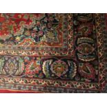 Large red ground Persian Mashad carpet with multi-coloured geometric, floral and foliate designs.