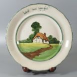 Llanelly pottery plate hand painted with a cottage in a landscape and marked 'Lest we forget',
