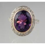 Amethyst and diamond ring . The oval amethyst surrounded by diamonds with diamond set shoulders.