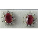 Pair of ruby and diamond cluster earrings. The oval rubies surrounded by diamonds. 12x11mm. Approx