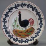 Llanelly pottery cockerel plate, having painted decoration within sponged foliate border. (B.P.