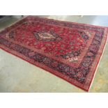 Red ground Persian Kashan carpet having floral and foliate designs. 194 x 307cm approx. (B.P.