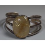 Silver bangle set with a large cabochon rutilated quartz. (B.P. 21% + VAT)