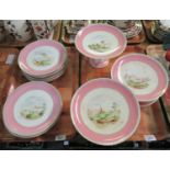 Two trays of 19th Century porcelain plates and tazzas with pink banding and central landscape