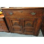 Oak sideboard, the moulded top above a single drawer with two blind panelled doors, carved with