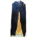 Early 20th Century black velvet opera cape with padded and ruched collar and golden silky lining. (