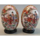 Pair of modern Chinese porcelain eggs decorated with reserved panels of figures in a boat on a lake.