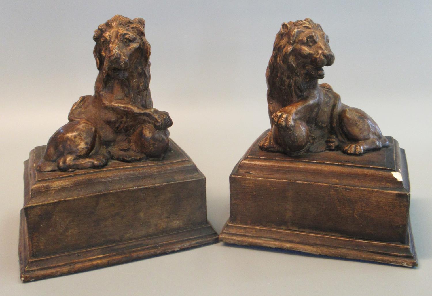 Pair of antiqued loaded plaster bookend type studies of male lions with front paw upon ball on