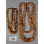 Two strings of amber coloured resin beads. (B.P. 21% + VAT)