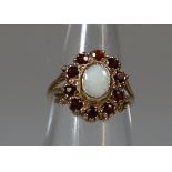 9ct gold opal and garnet oval-shaped dress ring with split shoulders. 1.5g approx. (B.P. 21% + VAT)