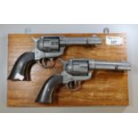 Pair of diecast metal Colt cowboy type cap firing revolvers on a display panel. (2) (B.P. 21% + VAT)