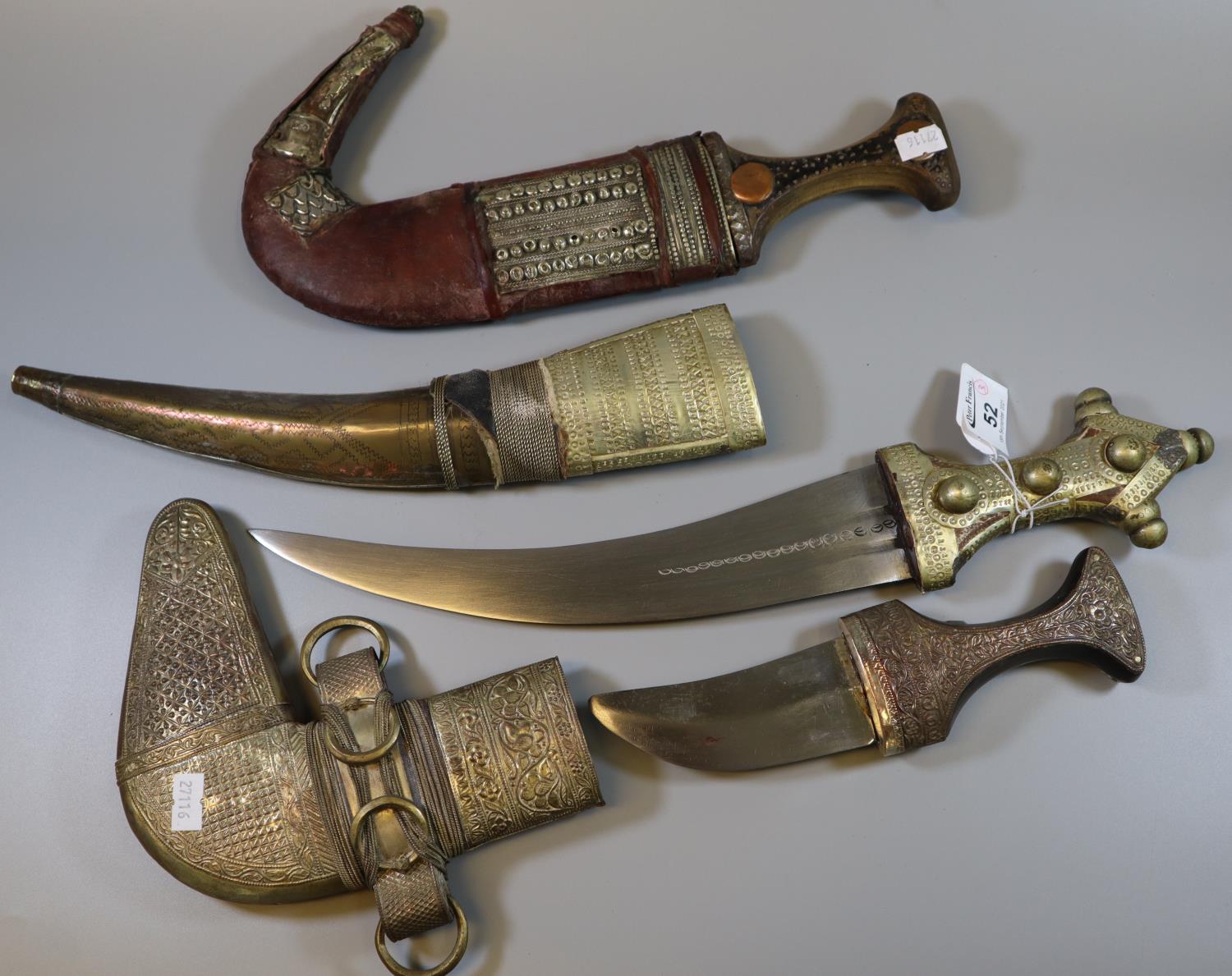 Three Arab jambiya type ceremonial daggers with overall white metal decoration, wooden hilts and