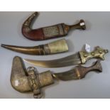 Three Arab jambiya type ceremonial daggers with overall white metal decoration, wooden hilts and