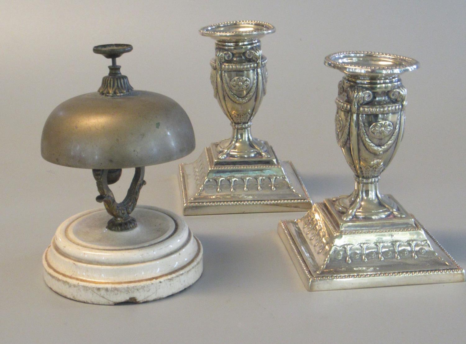 White metal reception bell on ceramic base, together with a pair of silver plated repousse decorated