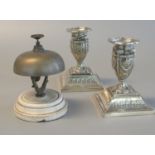 White metal reception bell on ceramic base, together with a pair of silver plated repousse decorated